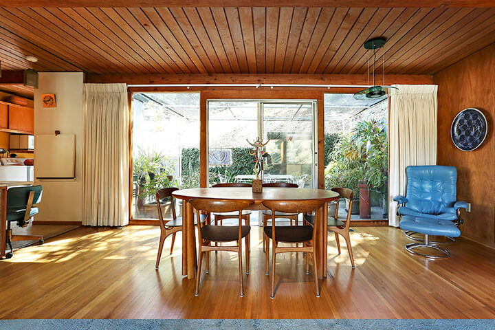 The dining room has a wooden floor and ceiling and an outside view