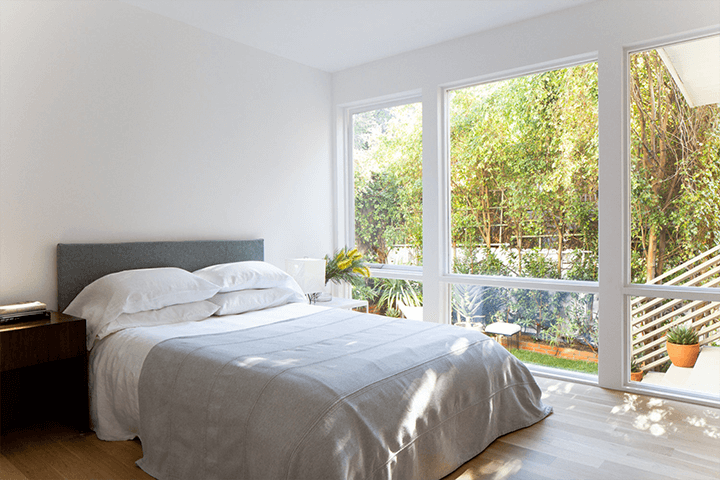 A bedroom with a large glass window that offers a beautiful view of the outside.