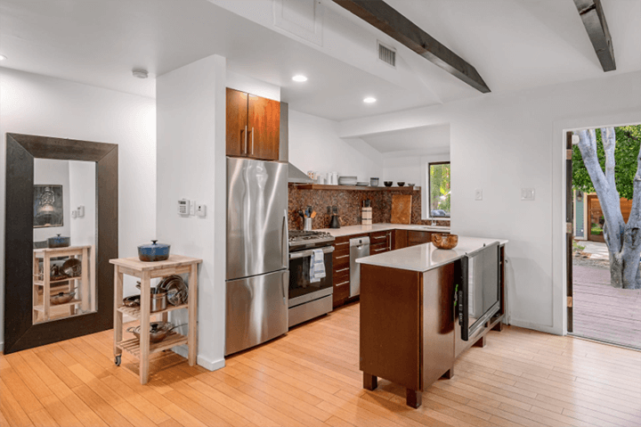 The kitchen has a wooden floor, a fridge, a chimney, and a wooden rack.