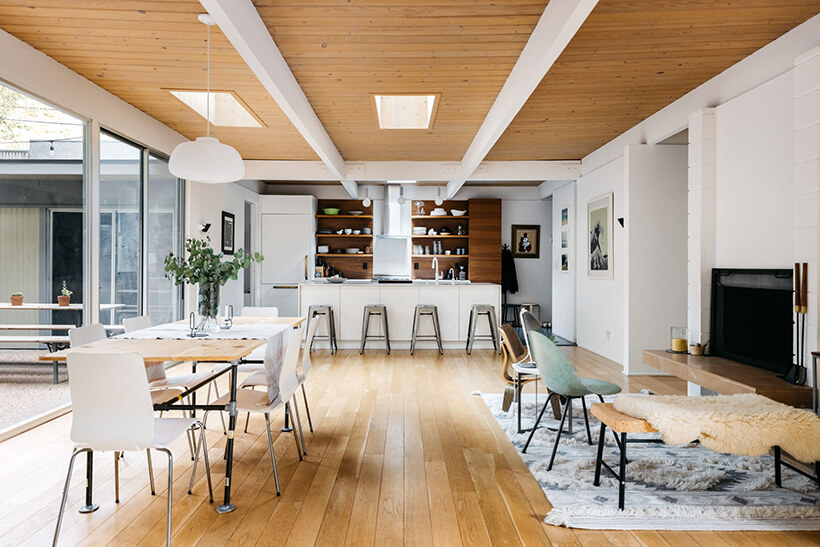 Dining room and kitchen with wood shelves, wrap-around decks, and wood floors