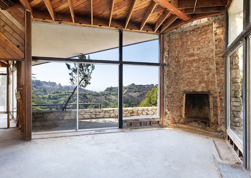 A down to the studs interior with a brick fireplace with views of the surrounding hills.