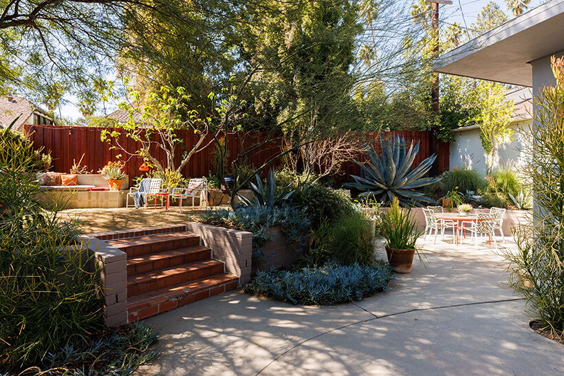 Drought tolerant professionally landscaped yard with patio areas shaded by mature trees and an array of succulents. 