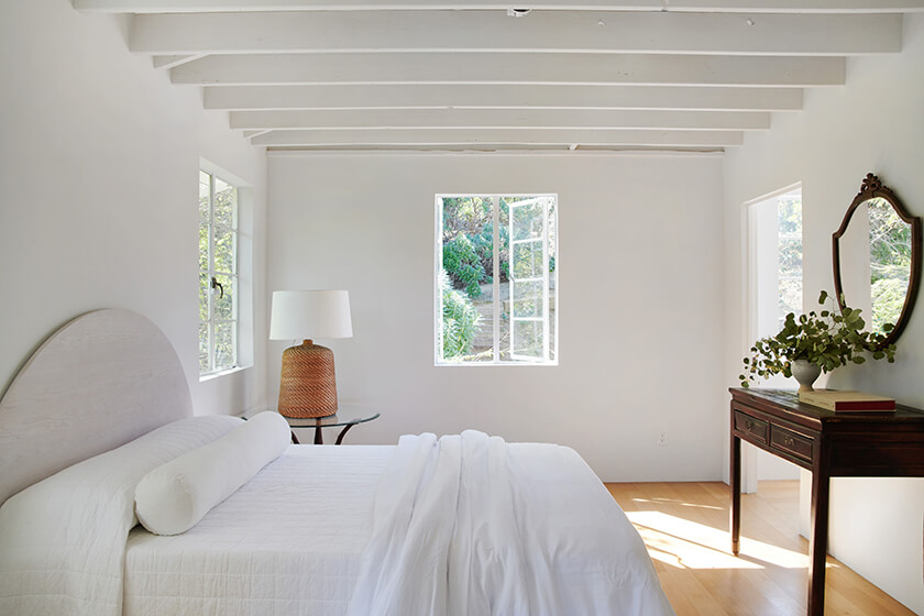 Bedroom with wooden ceiling beams and windows